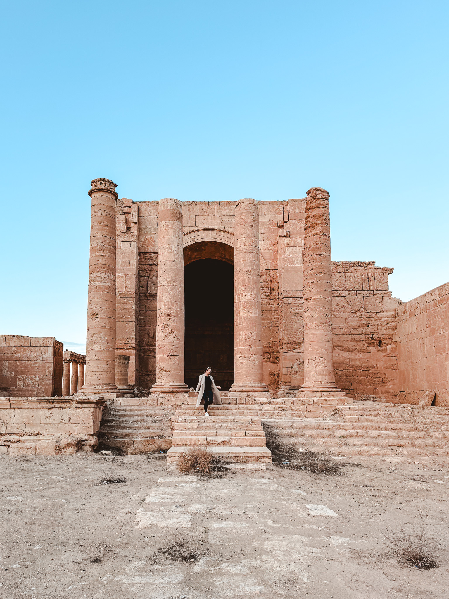 A woman stands in front of the ancient Roman-style ruins of Hatra in norther