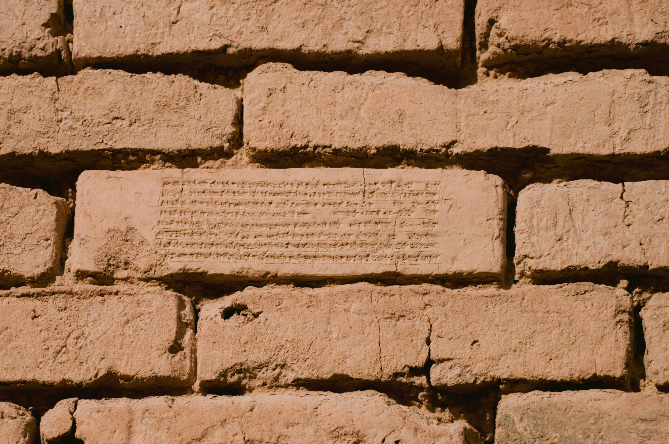 Close-up of ancient mud bricks at Babylon, Iraq, featuring visible cuneiform inscriptions from the Neo-Babylonian era.