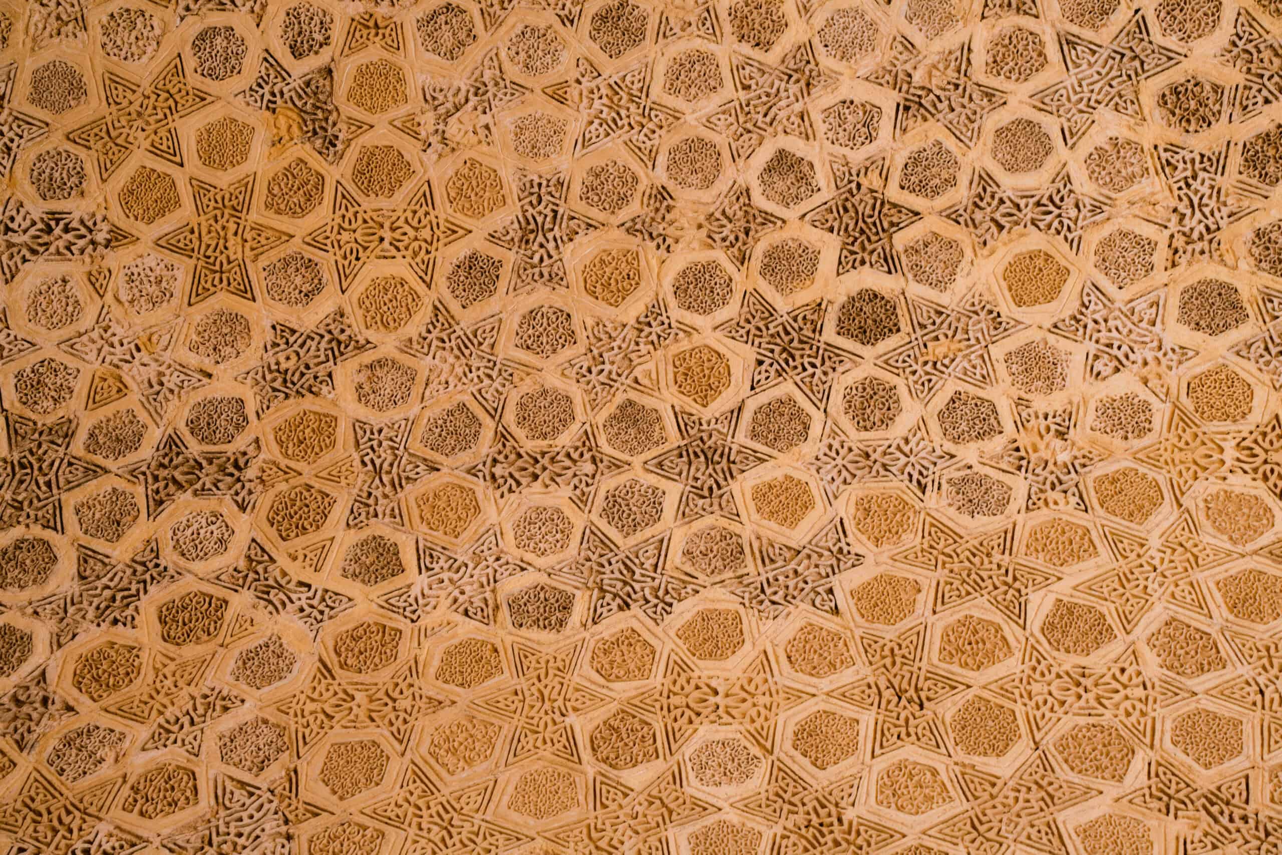 Close-up of intricate geometric ceiling patterns at Al-Mustansiriya School in Baghdad, showcasing detailed Islamic star motifs and Arabic calligraphy in carved stucco.
