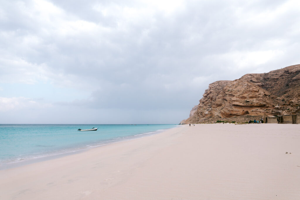 Pristine Shoab Beach on Socotra Island, Yemen, with powdery white sand, turquoise Arabian Sea waters, and dramatic rocky cliffs — a top spot for relaxation.