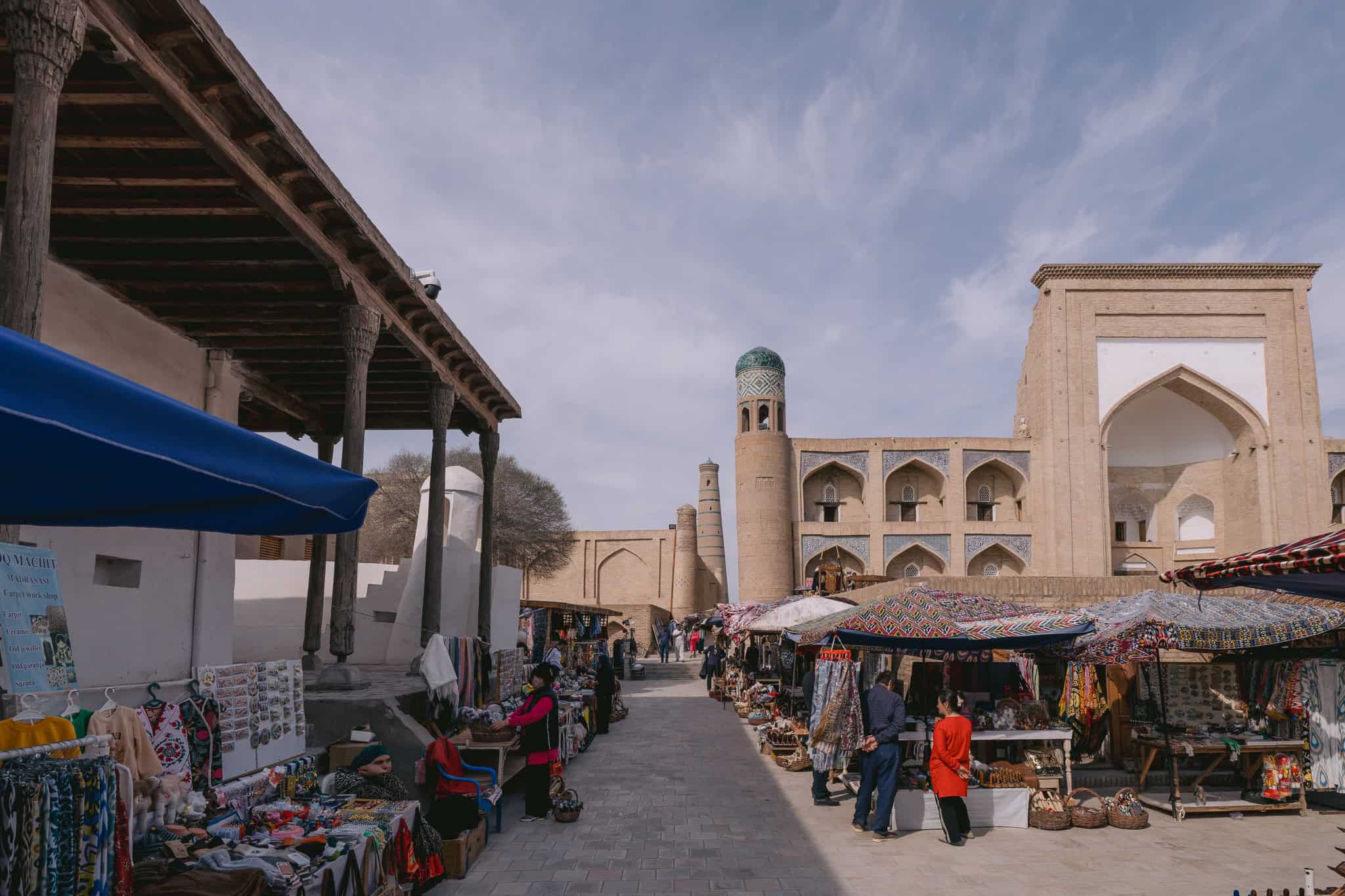 Bazaar in Khiva, Uzbekistan with local textiles and souvenirs against Islamic architecture.
