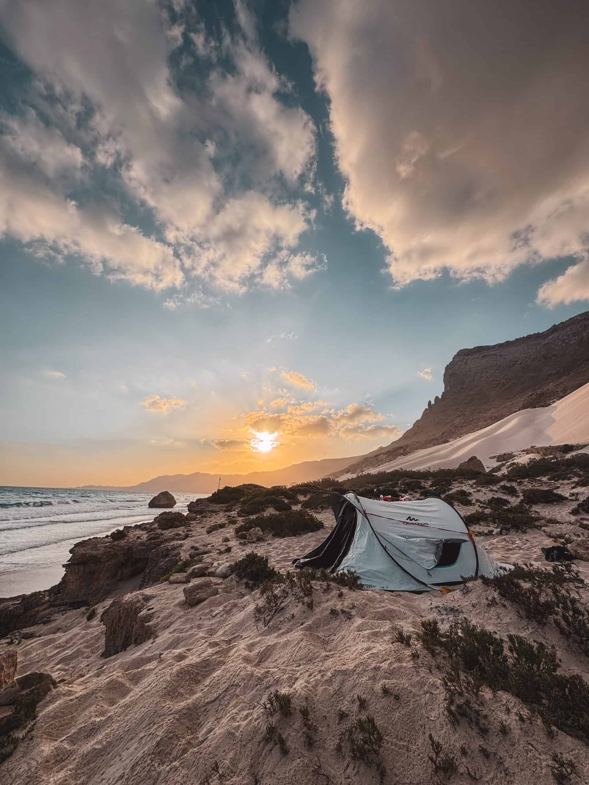 Tent pitched on Arher Beach at sunset with sand dunes and ocean, Socotra Island.