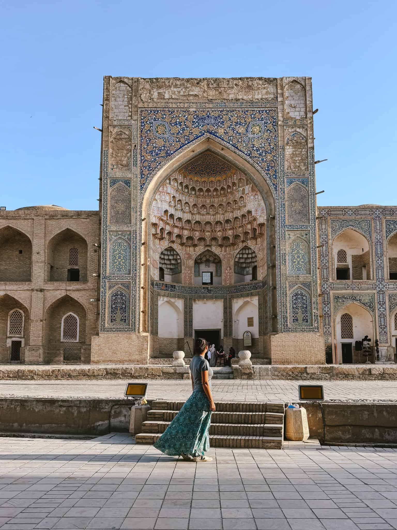 Woman standing alone in front of an ornate madrasa in Bukhara, demonstrating that Uzbekistan is safe for solo female travelers.