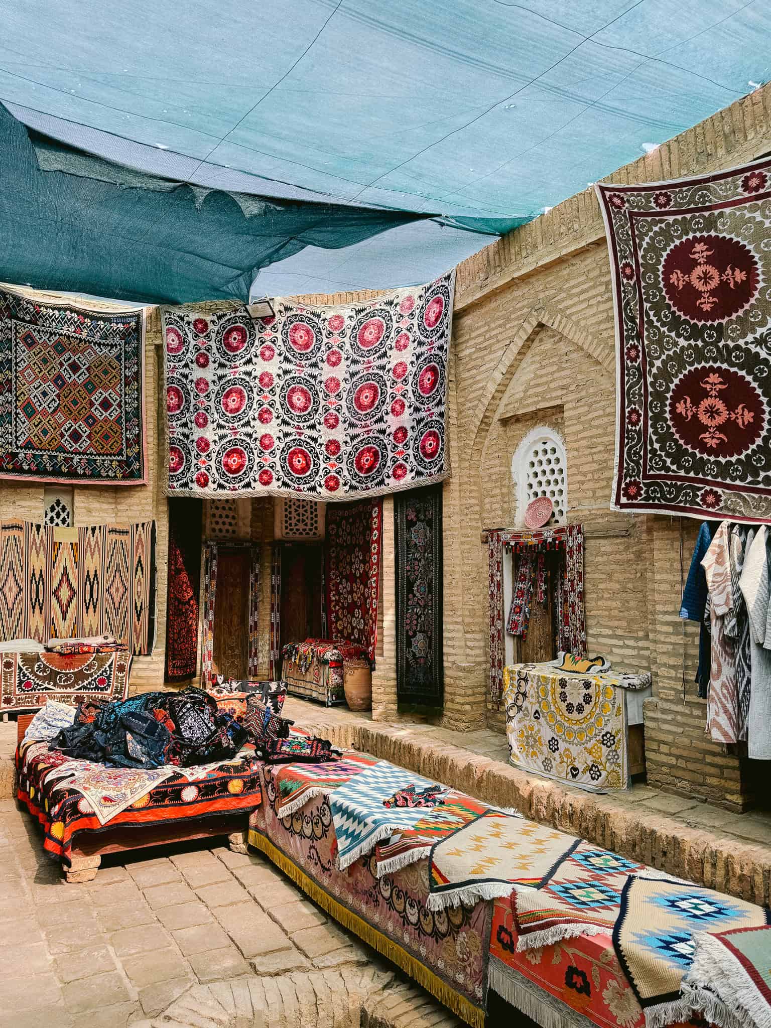 Colorful handwoven carpets and textiles on display in a traditional bazaar in Khiva — a vibrant place to shop for Uzbek crafts.