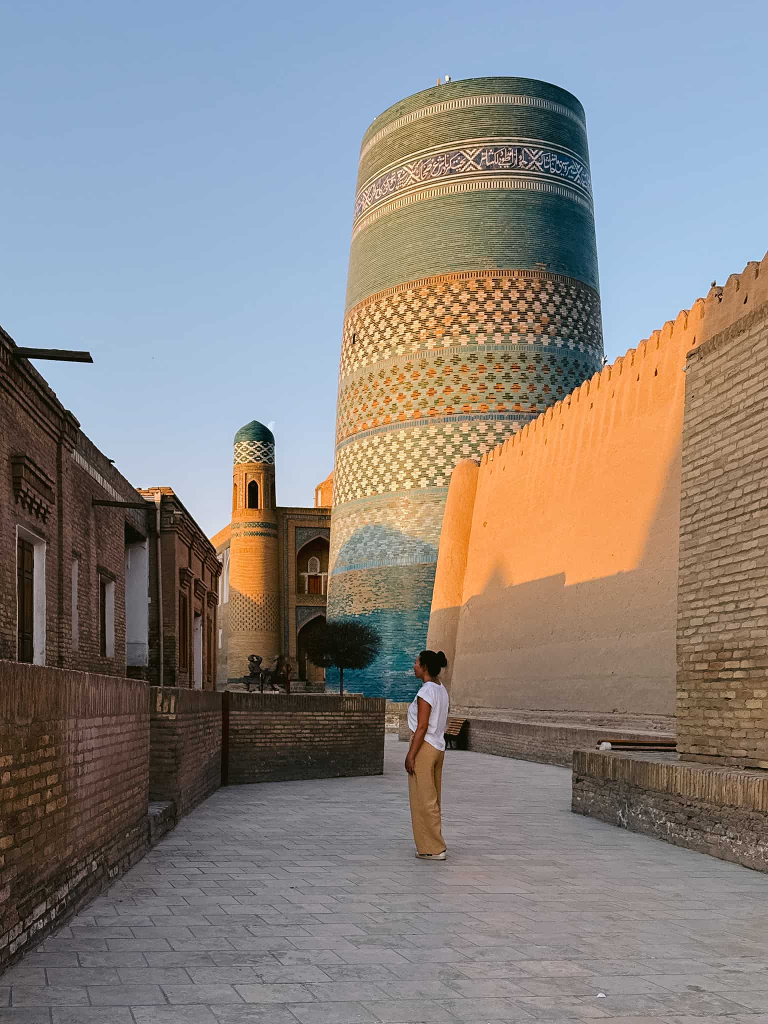 Traveler standing near the turquoise-tiled Kalta Minor Minaret in Khiva’s Itchan Kala — an unmissable landmark on any Uzbekistan itinerary.