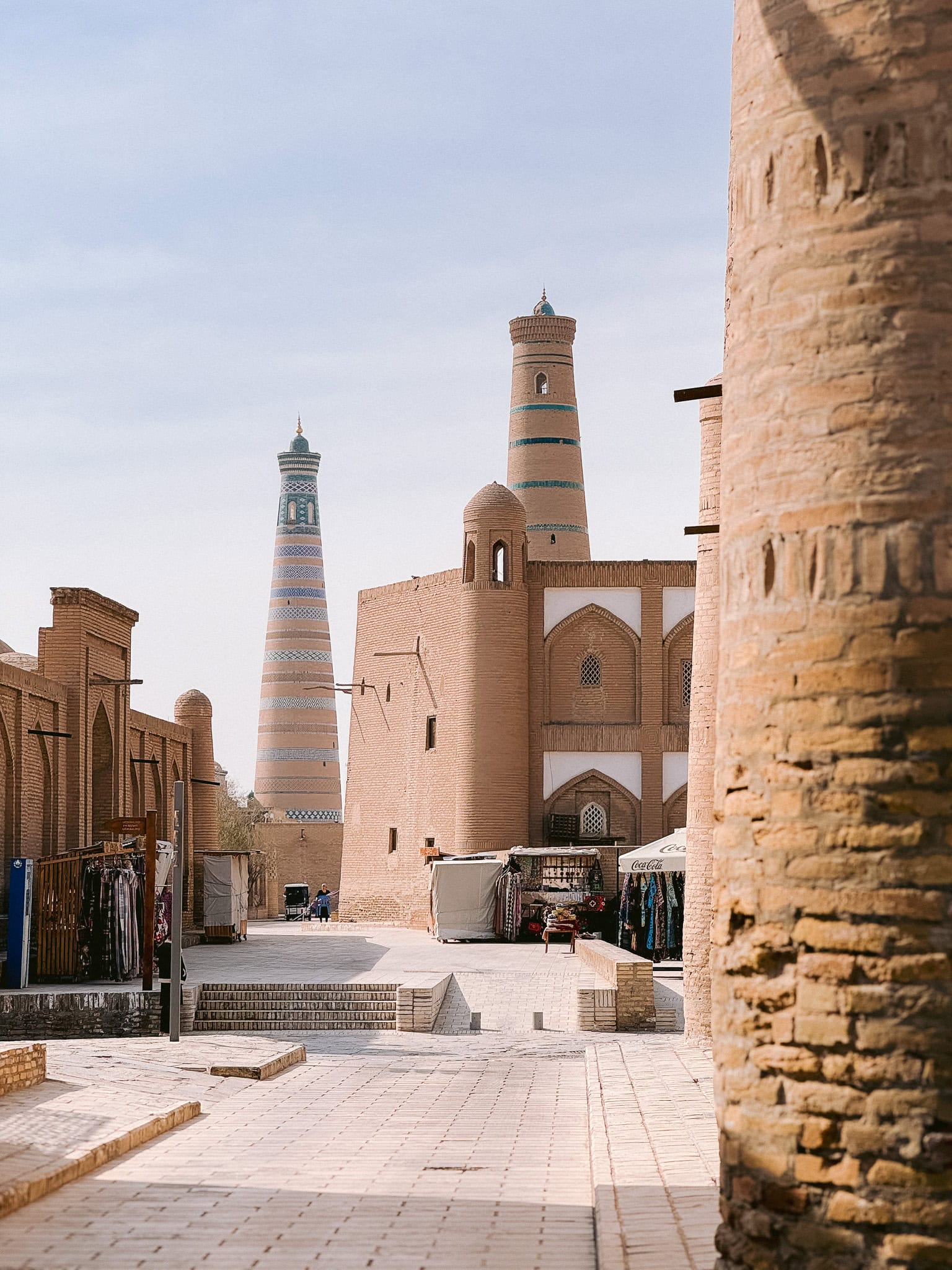 Peaceful alleyway inside Khiva’s walled city with twin minarets rising behind — a glimpse into everyday life in Uzbekistan’s Silk Road gem.