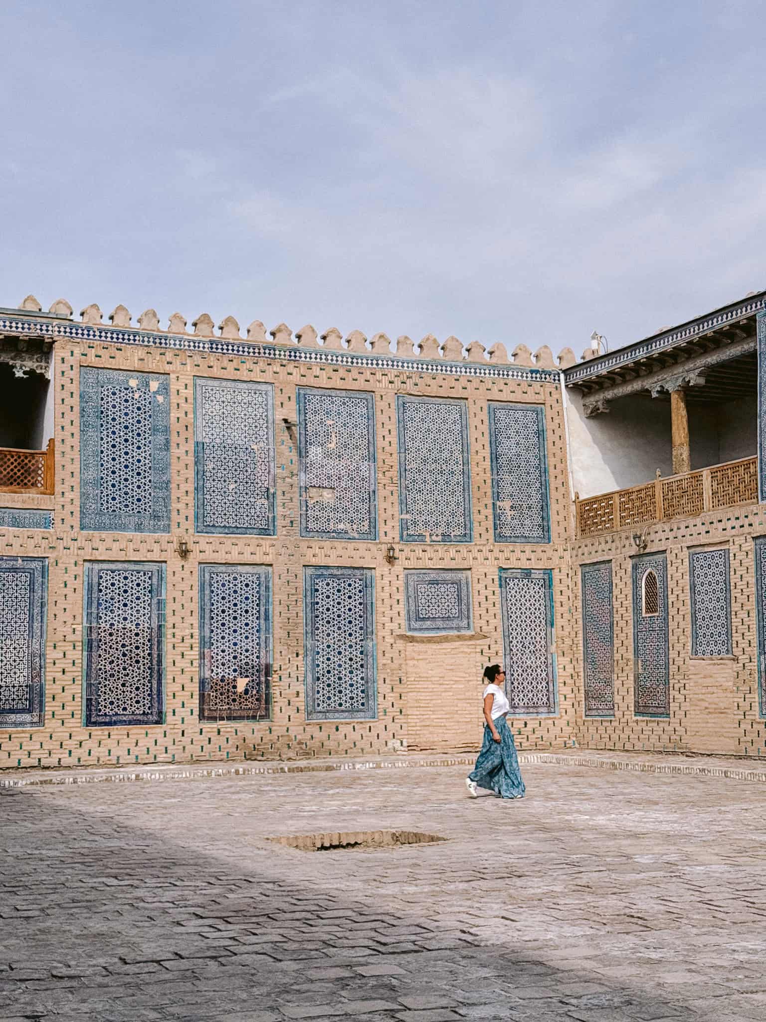 Traveler walking through the tiled courtyard of Tash Khauli Palace in Khiva, Uzbekistan — one of the city’s most beautiful royal residences.