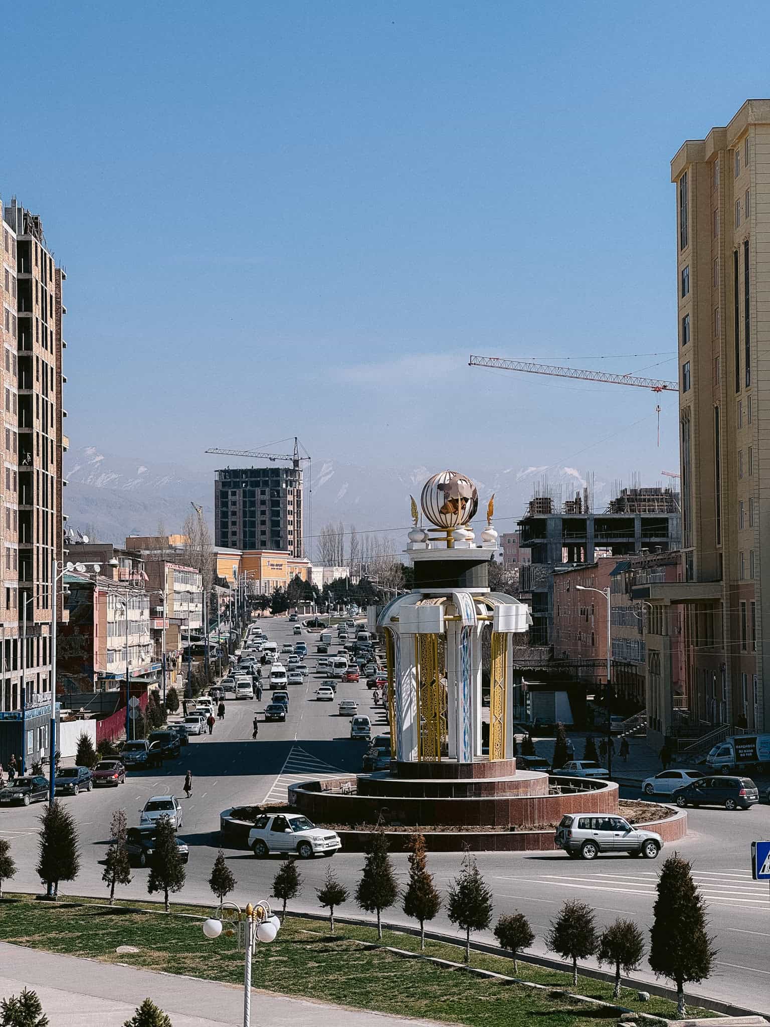 Panjakent Tajikistan city center with traffic, monument and snow capped mountains in the background