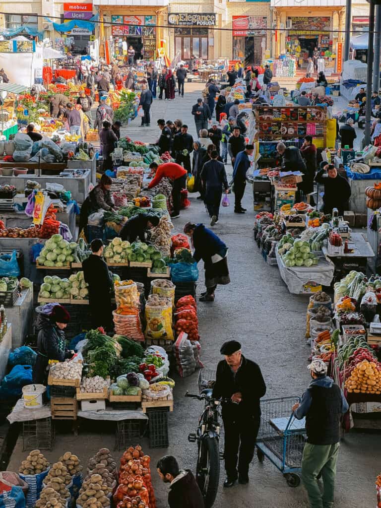 Fresh produce stalls at a local market in Bukhara with vendors selling vegetables and herbs